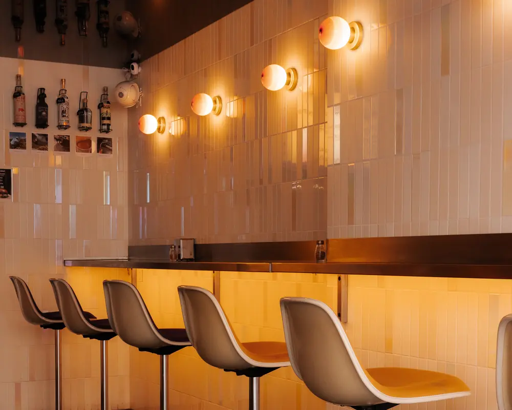 The counter in Saint-Germain-des-Prés: Eames stools, cream tiles and orange globe lamps