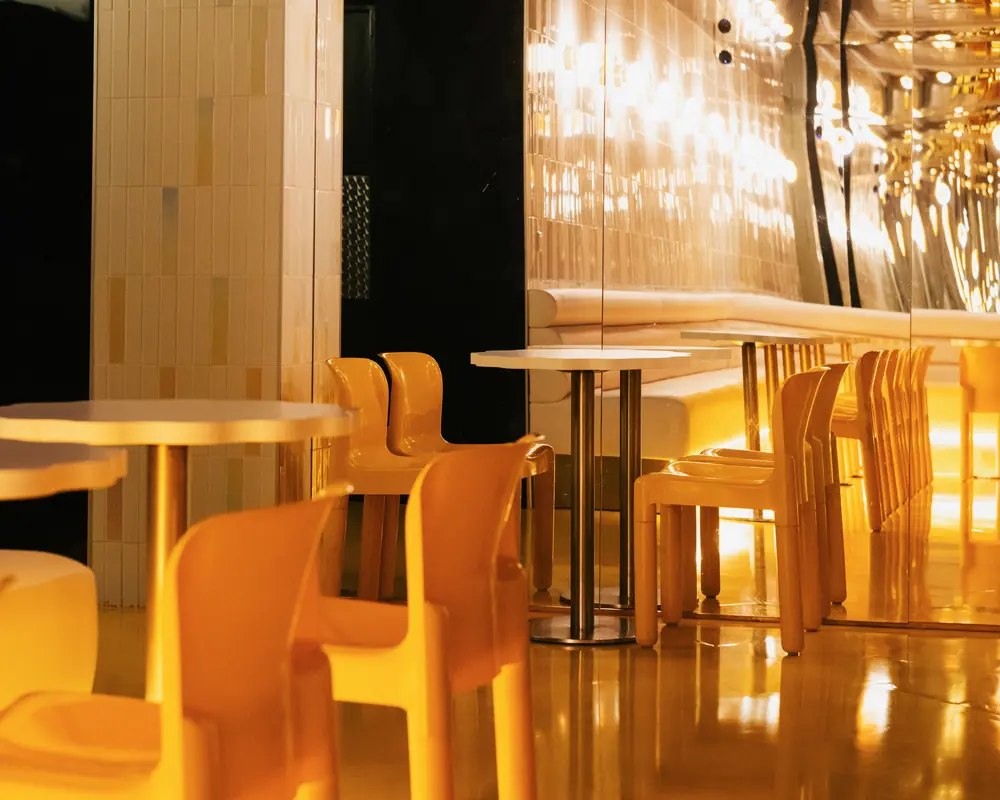 The Pigalle room: yellow chairs, white tables and mirrored walls